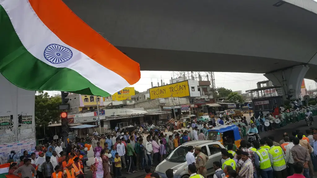 Crowd gathered under an elevated roadway with an Indian national flag