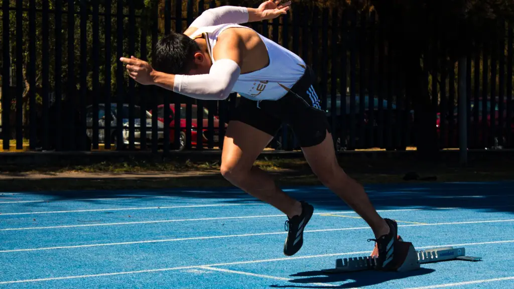 Athlete exploding out of the blocks on a blue running track