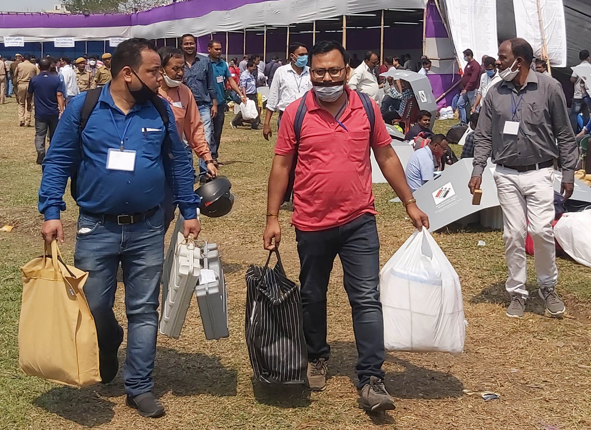 Polling officials carrying EVMs at a distribution centre