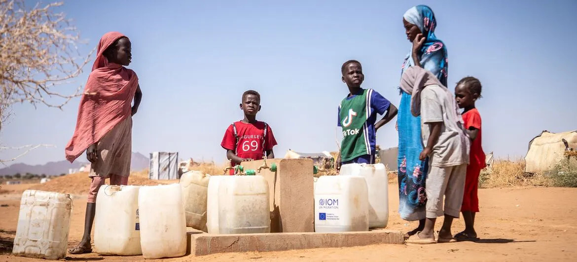 Sudan war: Women and children collect water at a water point in an arid part of Sudan