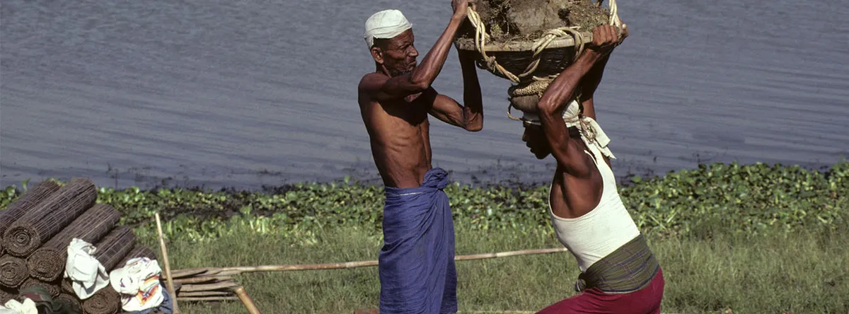 Eradication of Poverty: Workers carry loads near a riverbank, an image used by the UN for its poverty day observance