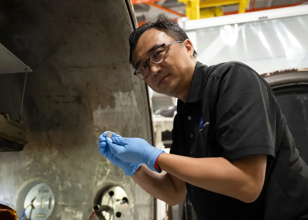 NASA Moon battery: Yi Lin holds a SPEARS coin-cell battery after thermal vacuum testing